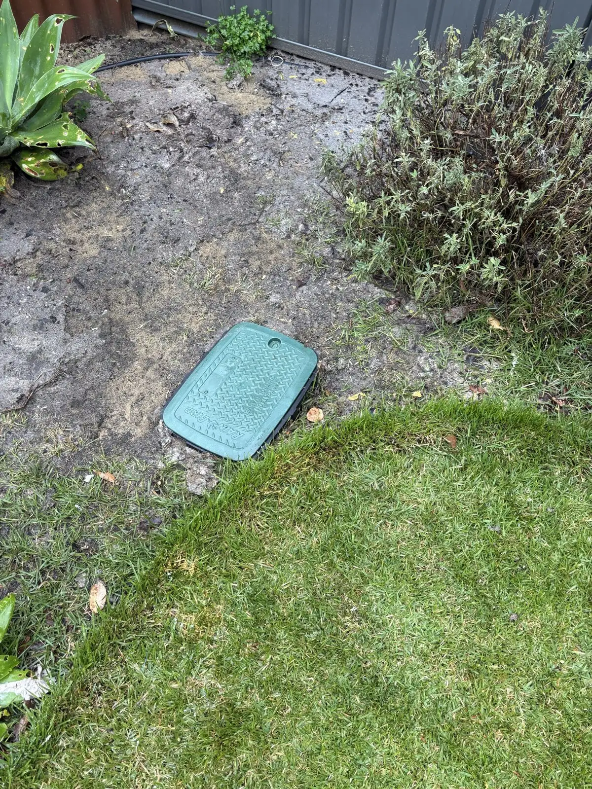 The sewer inspection shaft cover in an Edgewater garden bed, the only access point the reline needed.