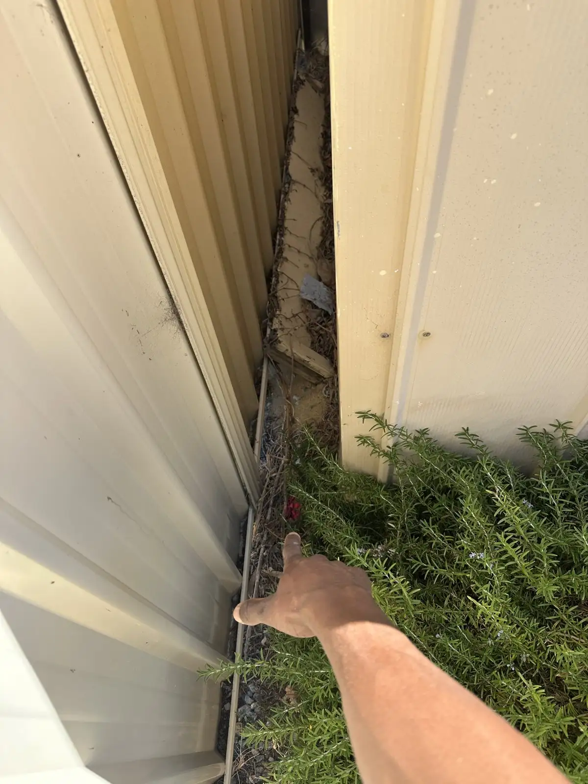A narrow side passage between a Mandurah unit and the fence, with a hand pointing to where the sewer line runs.